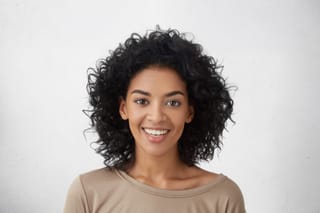 close-up-shot-pretty-woman-with-perfect-teeth-dark-clean-skin-having-rest-indoors-smiling-happily-after-received-good-positive-news.jpg